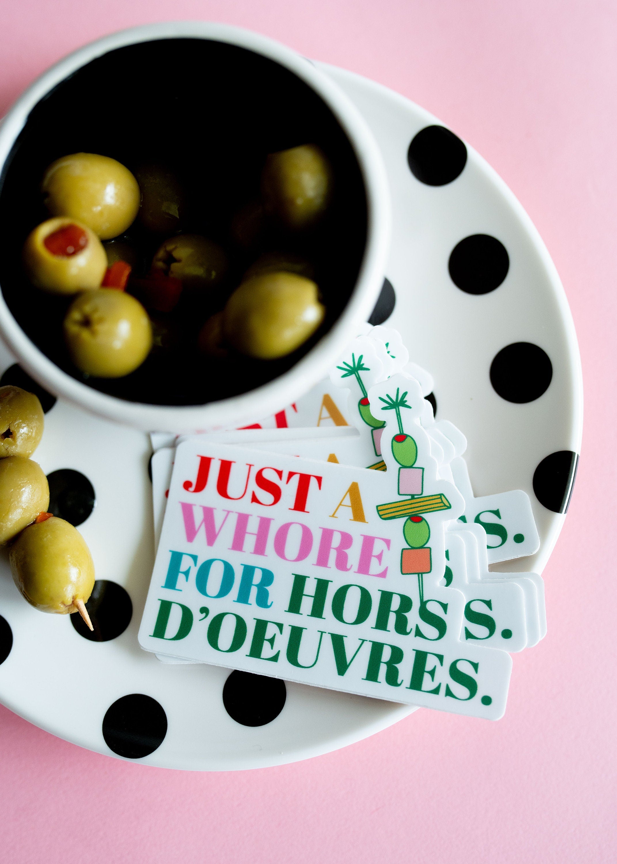 Funny stickers on a plate with green olives nearby.