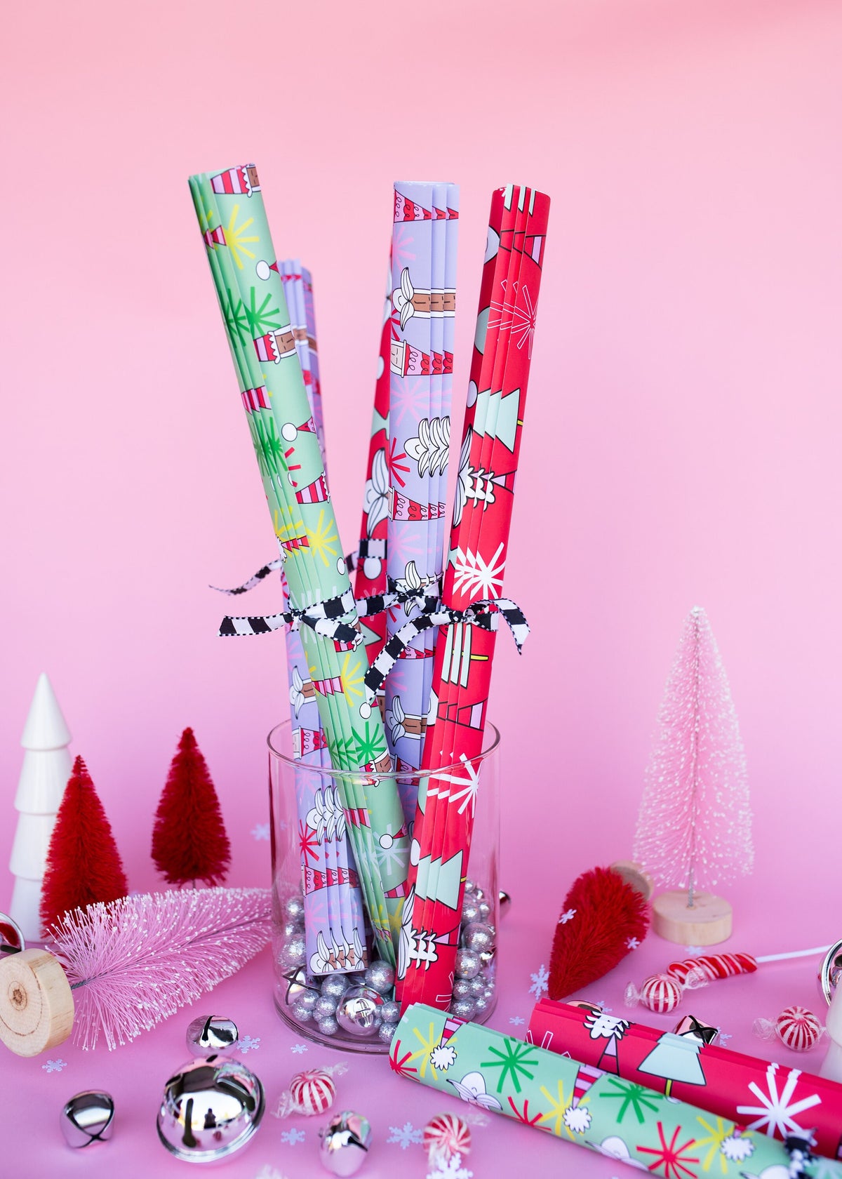 Several rolls of holiday wrapping paper standing in a vase on display.