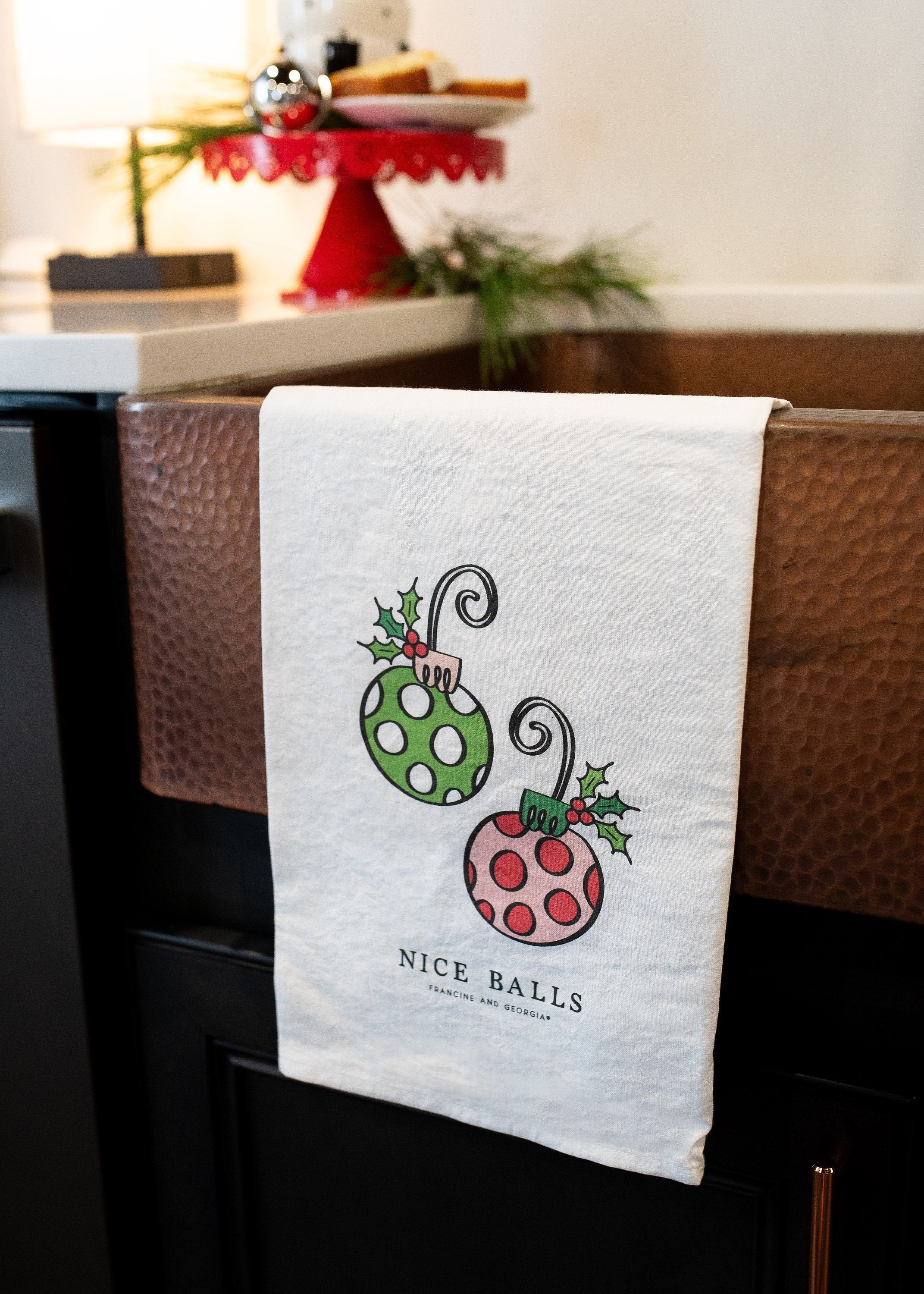 A holiday tea towel with two ornaments on it.