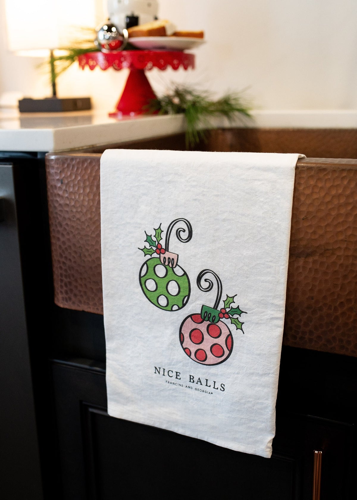 A holiday tea towel with two ornaments on it.