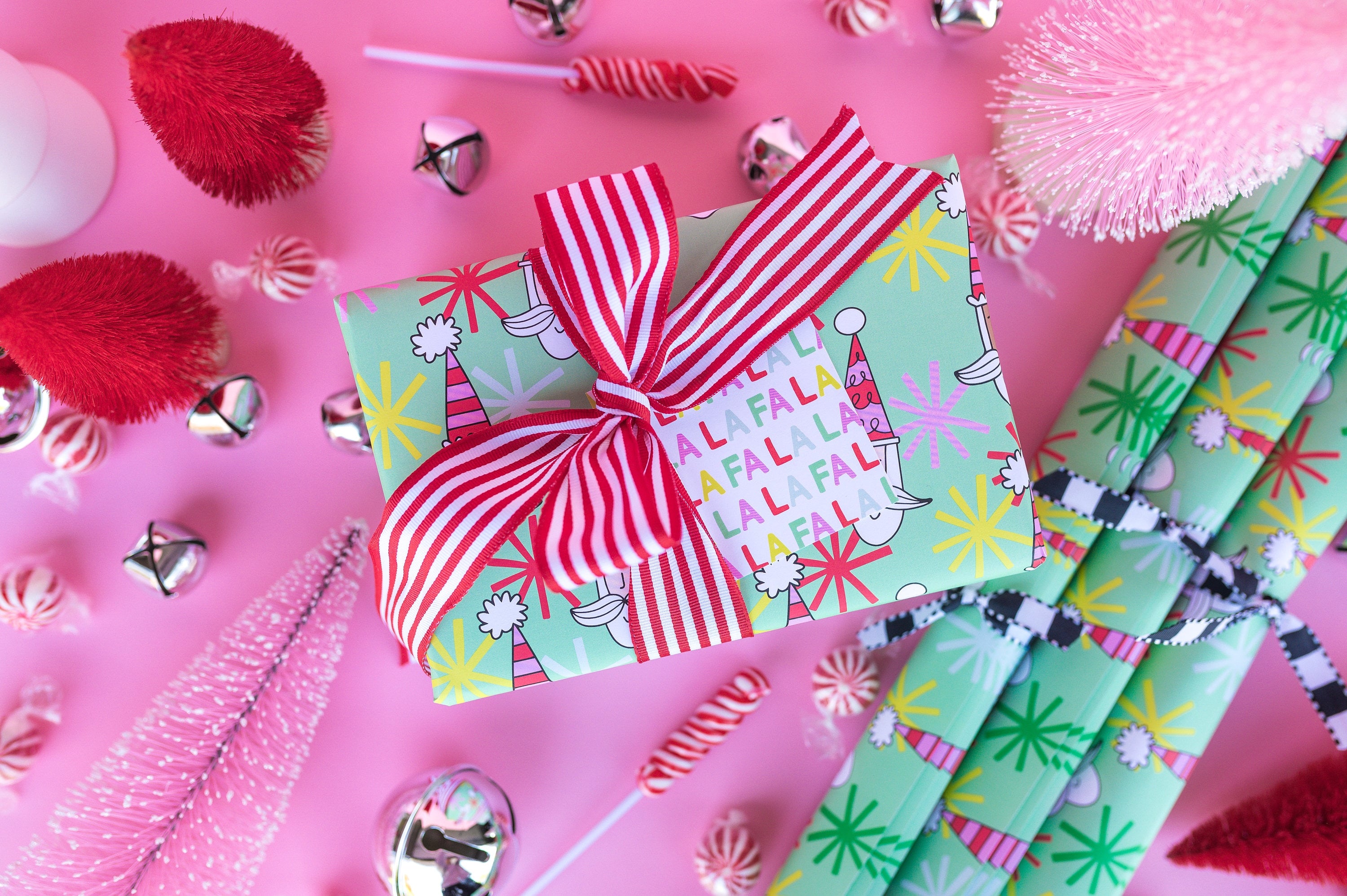 A Christmas gift wrapped in light green paper with a red and white striped bow.